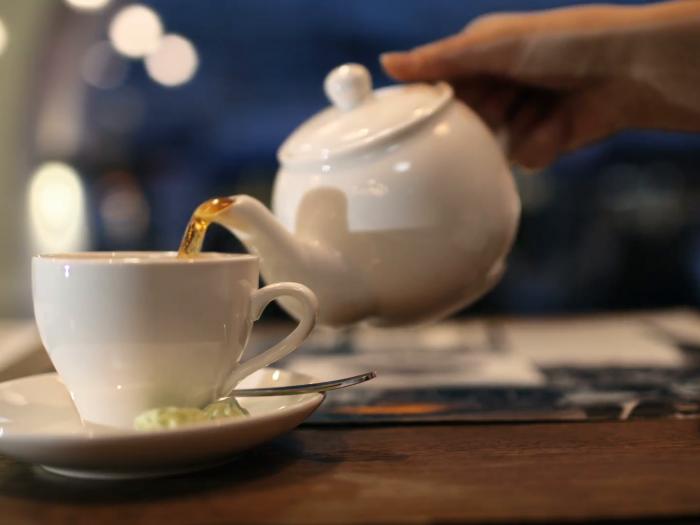 close-up-shot-of-female-hand-pouring-black-hot-tea-from-the-pot-into-the-cup_xk8fqbyb__F0000