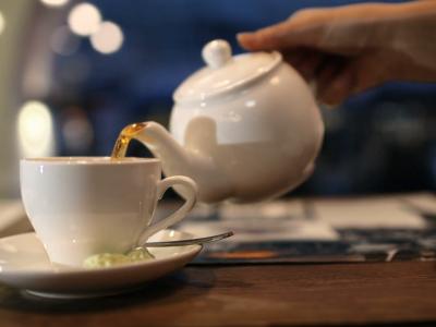 close-up-shot-of-female-hand-pouring-black-hot-tea-from-the-pot-into-the-cup_xk8fqbyb__F0000
